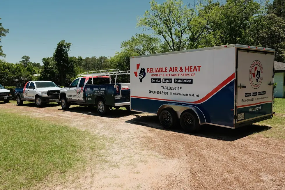 Two branded Reliable Air & Heat pickups and the branded box trailer on open ground under a blue Texas sky