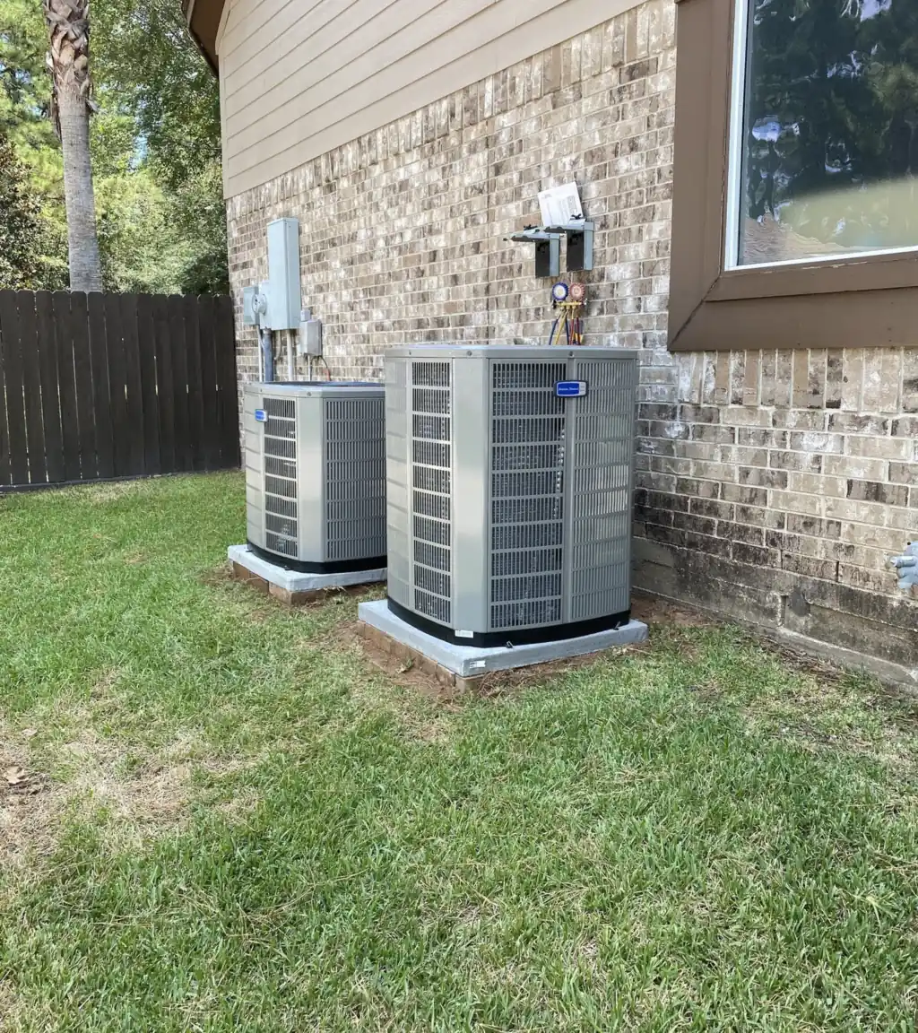 Two American Standard condensers on new pads against a brick wall with manifold gauges connected