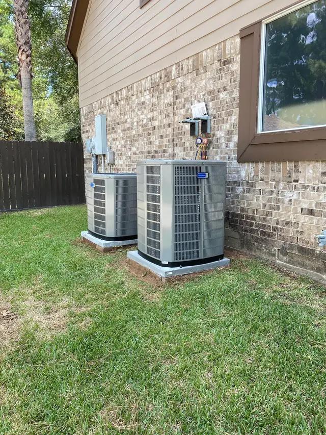 Twin American Standard condensers beside a house